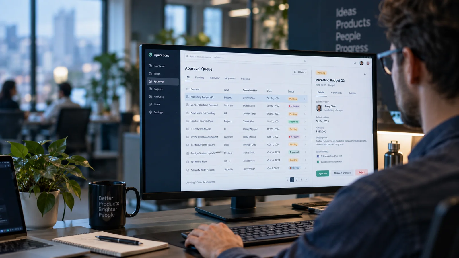 A widescreen business web application with a detailed approval queue, task rows and record side panel, photographed over the shoulder of a product engineer in a modern office